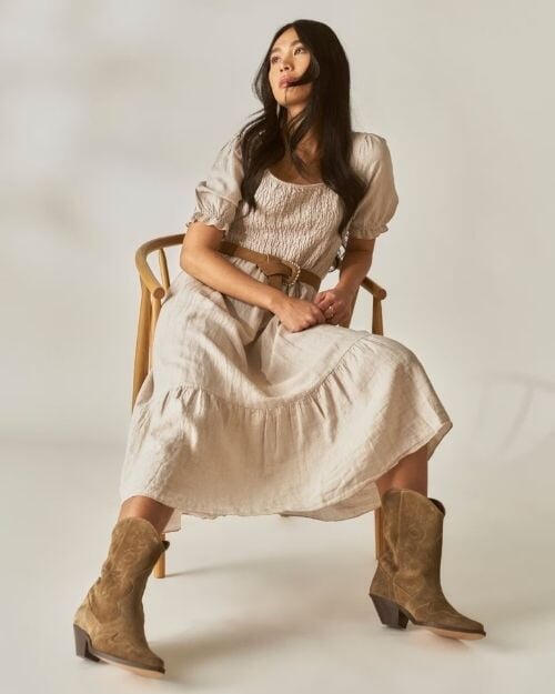 Beige linkjole med smock-detaljer, puffermer og camelfarget belte kombinert med cowboystøvler – western boho lin dame | FLOYD.no